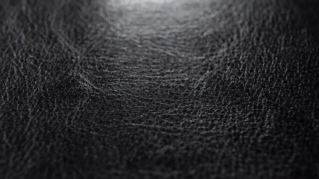Black wrinkled leather textured surface. Macro. Slow rotation