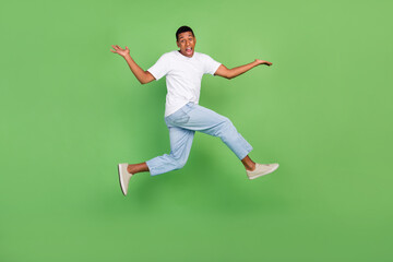 Fototapeta na wymiar Full body profile side photo of young african guy jump up puzzled isolated over green color background