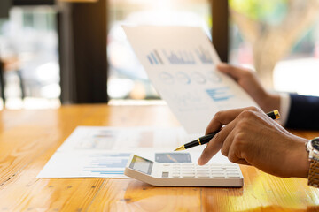 a businessman pressing his finger on a calculator to calculate expenses Finance is calculating tax information. and analyze financial stock charts that are in good shape with growth and progress.