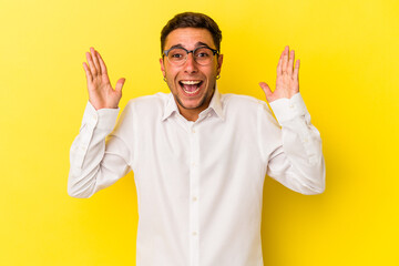 Young caucasian man with tattoos isolated on yellow background  receiving a pleasant surprise, excited and raising hands.