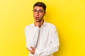 Young caucasian man with tattoos isolated on yellow background  looking sideways with doubtful and skeptical expression.