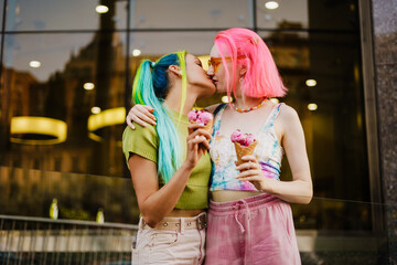 Young lesbian couple kissing while eating ice cream together