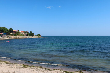 Fototapeta premium Coastal view of Nesebar old town houses and embankment with sandy beach. Nesebar Bulgaria. Ancient town on the Black Sea coast, UNESCO