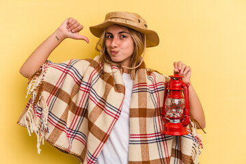 Young caucasian holding lantern isolated on yellow background  feels proud and self confident, example to follow.