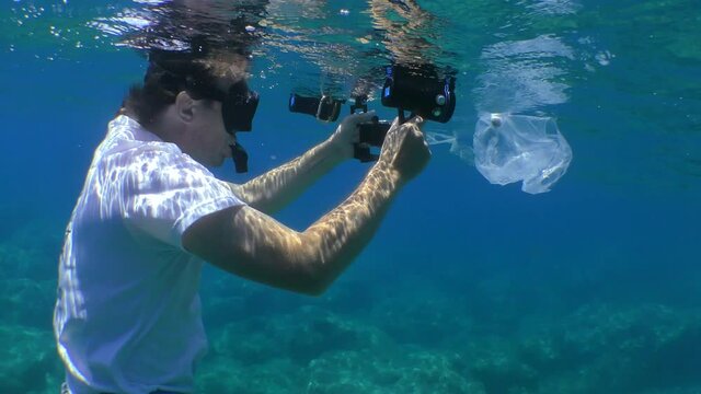 Plastic pollution: an underwater operator films a plastic bag in which a fish gets entangled and died.