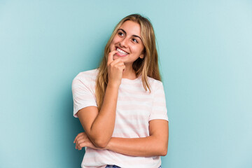 Young caucasian blonde woman isolated on blue background  relaxed thinking about something looking at a copy space.