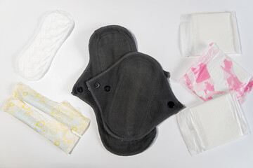 Dos compresas menstruales de algodón reutilizables junto a las tradicionales almohadillas y tampones sobre un fondo blanco. Concepto de períodos cero residuos - obrazy, fototapety, plakaty