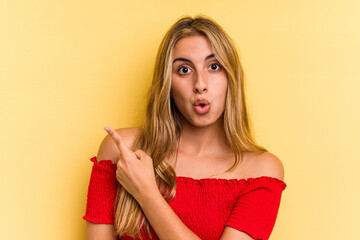 Young caucasian blonde woman isolated on yellow background  pointing to the side