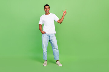Fototapeta na wymiar Full body photo of young african guy indicate finger empty space suggest direct way advert isolated over green color background