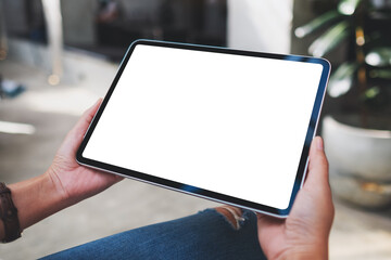 Mockup image of a woman holding digital tablet with blank white desktop screen in cafe