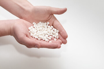 A lot of white round pills in a hands. Vitamin pills.