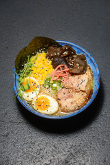 ramen soup in blue plate on black background
