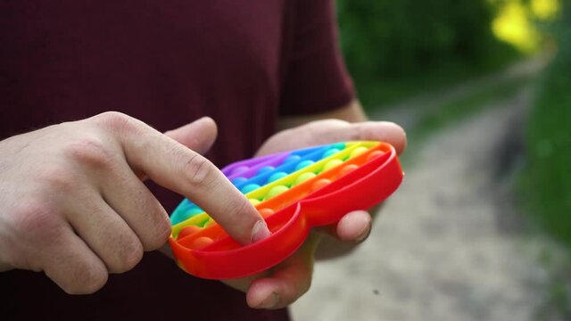 man playing with toy pop it simple dimple sitting in the park