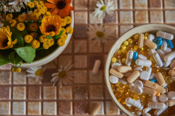 A ceramic bowl with medicinal herbs and a bowl with various pills and tablets are on the countertop.