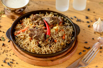 Uzbek pilaf in a pan on the table with spices
