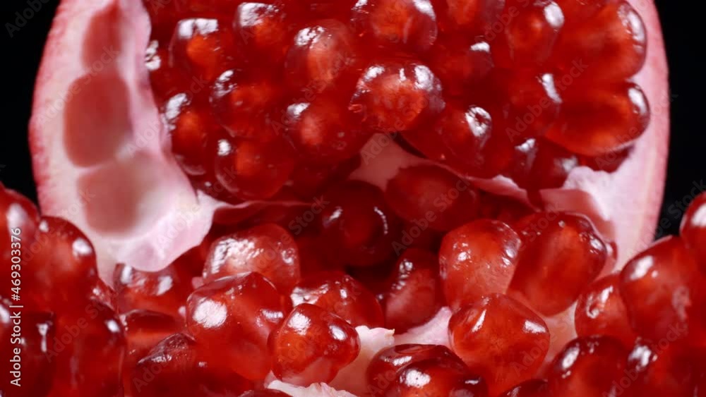 Wall mural footage of rotating red pomegranate seeds on black background