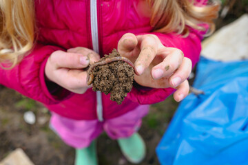 Hands of child holding soil with earthworm
