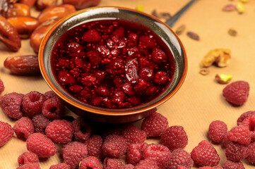 raspberry jam in a small brown gravy boat on a background with raspberries
