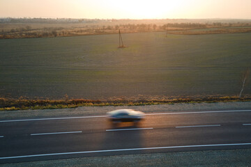 Aerial view of intercity road with blurred fast driving environment friendly electric car at...
