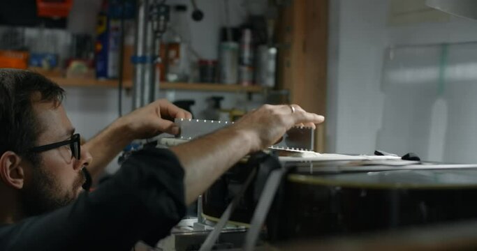 Luthier adjusts the fretboard angle in the electric guitar mounted on the jig, repairing the musical instruments at hte shop, 4k 60p 10 bit