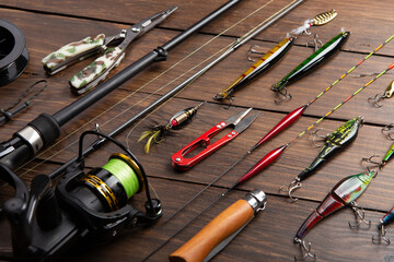 Fishing tackle - fishing spinning rod, hooks and lures on wooden background. Active hobby...