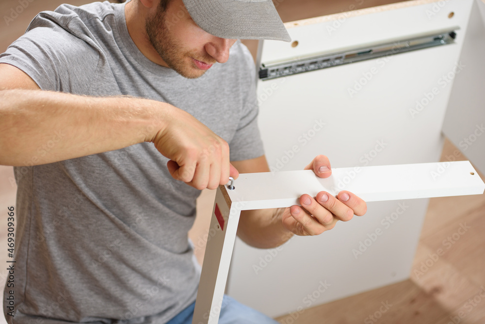 Wall mural A man assembles a new table with a tools. Handyman