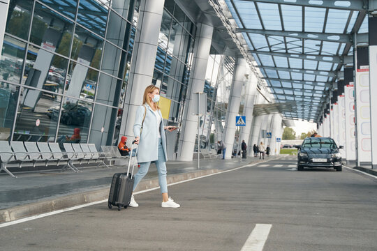 Stylish female passenger with baggage crossing street