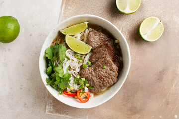 Vietnamese Pho-bo soup. Rice noodles and beef. Serving Asian food. Vietnamese food. Limes