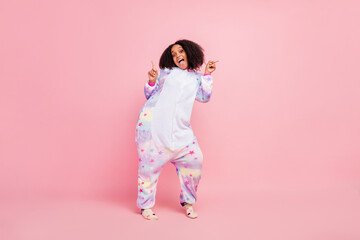 Full size photo of young african woman have fun indicate fingers empty space overall warm isolated over pink color background