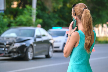 Sad female driver speaking on sellphone on street side calling for emergency service after car...