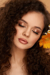 Elegant woman with flowers in curly hair. Pretty girl with perfect make-up. Close-up studio beauty face portrait. Young beautiful fashion model with closed eyes