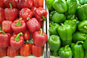 Obraz na płótnie Canvas Green and red color fresh capsicums display on shelf at market place.