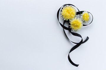 Decoration from black funeral ribbon with yellow flowers.
