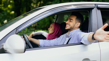 Fototapeta na wymiar Happy Owners. Cheerful Middle Eastern Couple Enjoying Ride In Their New Car