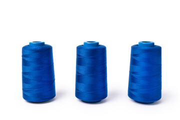 Threads of trendy electric blue on a white background. Side view of three spools of sewing thread.