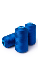 Threads of trendy electric blue on a white background. Side view of a bobbin of sewing thread. Vertical photo
