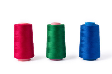 Pink, blue and green threads on a white background. Side view of colored sewing thread bobbins.