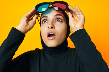 cheerful woman in black hijab popcorn 3D glasses cinema yellow background