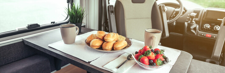 Breakfast with fruit and buns on the table in a camper van