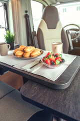 Breakfast with fruit and buns on the table in a camper van