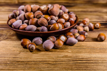 Plate with pile of hazelnuts on a wooden table