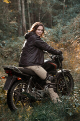 Fototapeta na wymiar a woman on a motorcycle in nature. motorcyclist walk through the forest