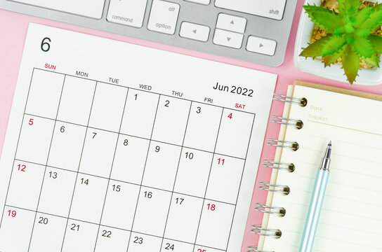June 2022 calendar sheet with keyboard computer on pink background.
