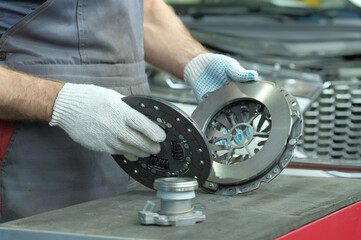 Spare parts for cars. Car clutch kit: drive disc, driven disc and exhaust bearing. An auto mechanic inspects the technical condition of the parts before installation.