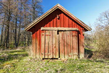 Old red wooden shed with crooked doors