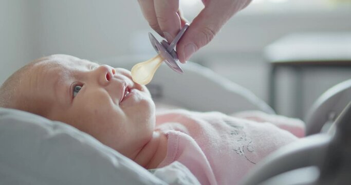 the baby is given a pacifier and he happily begins to suck it