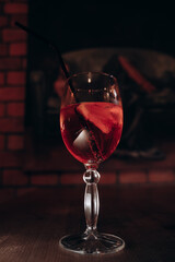 a red cocktail in a beautiful glass stands on a wooden table