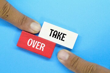 hand pointing at a colored board with the word Take Over