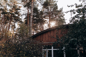 The sun is shining from behind the roof of a house in the woods