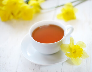 a cup of tea with yellow daffodils